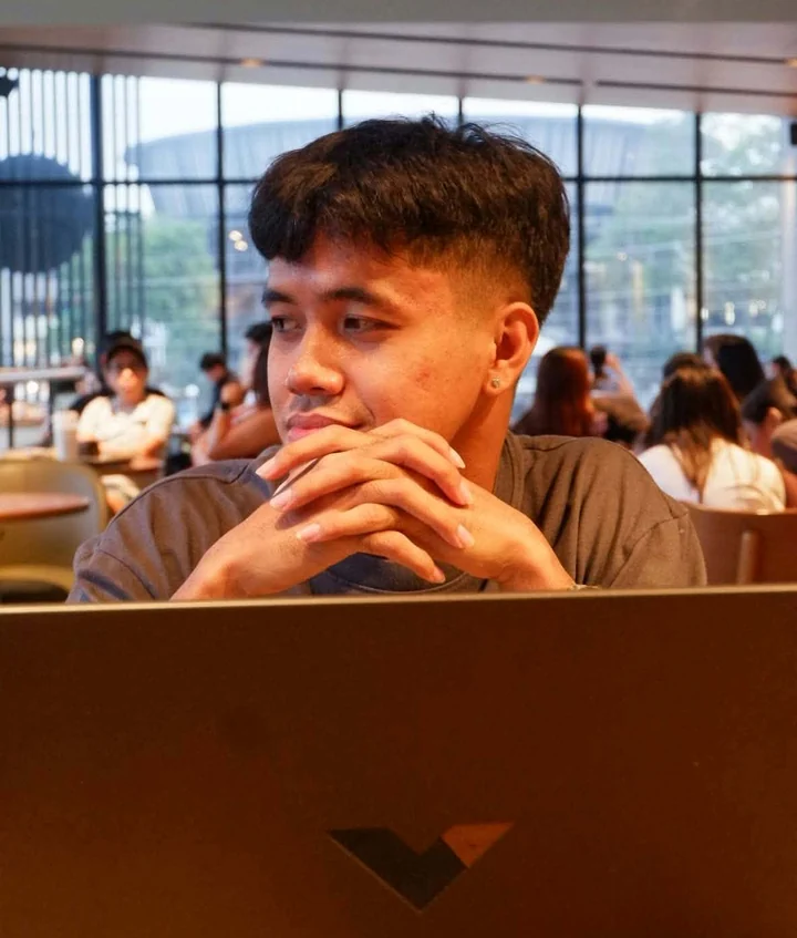 Jhade at a cafe table behind a laptop
